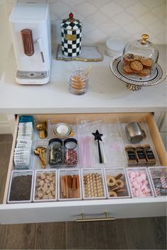 an organized drawer with cookies, donuts and other items in it on a white table