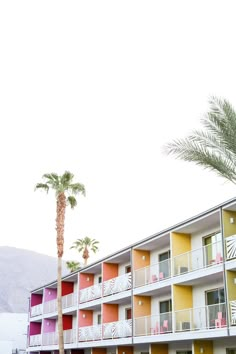 an apartment building with palm trees in the front and colorful balconies on the side