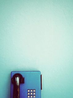 an old fashioned phone is on the wall in front of a light blue painted wall