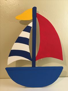 a blue and red sailboat on a white shelf next to a wall with a yellow sun behind it