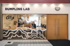 a woman is sitting at the counter in front of a building with writing on it