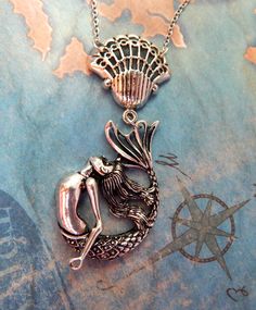 a necklace with a mermaid sitting on it's side and a map in the background