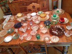 a wooden table topped with lots of glass plates and bowls on top of it's sides