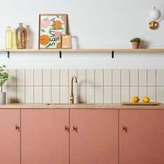 a kitchen with pink cabinets and white tiled backsplash, potted plants on the counter