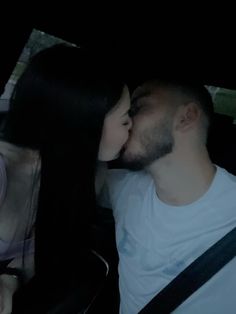 a man and woman are kissing in the back seat of a car at night time