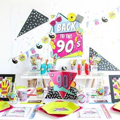 the table is set up for 90's birthday party with colorful decorations and paper streamers