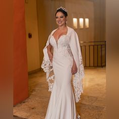 a woman in a wedding dress posing for the camera with her cape over her shoulders