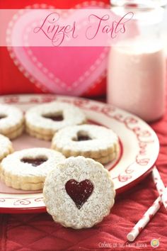 heart shaped cookies are on a plate next to a glass of milk