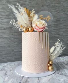 there is a pink cake with gold decorations on the top and flowers in the middle