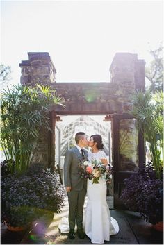 a bride and groom kissing in front of an archway at the end of their wedding day