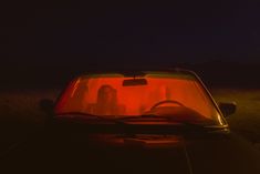 two people are sitting in the back of a car at night with their headlights on