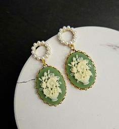 Beautiful vintage white floral cameos with light green backgrounds set in plated gold, paired with round faux pearl studs. Earrings have stud backs. Details: Earrings measure 45mm x 18mm Settings are plated brass Lightweight Pearls are plastic Lead and nickel free Cameos are vintage hard, matte resin For sanitary reasons these earrings CANNOT be returned Thank you for shopping Delicate Industry :) Vintage Green Flower Earrings, Green Vintage Flower Earrings For Gift, Green Vintage Flower Earrings As Gift, Jewelry Gift Ideas, Gift Ideas For Mom, Cameo Earrings, Cameo Jewelry, Unique Holiday Gifts, Earrings Flower