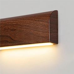 a wooden wall light that is on the side of a white wall and has a dim light coming from it