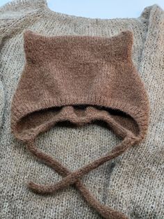 a knitted sweater with a cat's head on the front and tie at the back