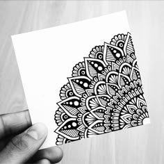 a hand holding up a piece of paper with black and white designs on it