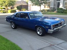 a blue car is parked on the side of the road in front of a house