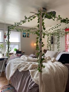 an unmade bed with ivy growing on the headboard and foot board, in a bedroom