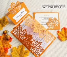 an orange and white wedding card with leaves on it, next to some autumn leaves