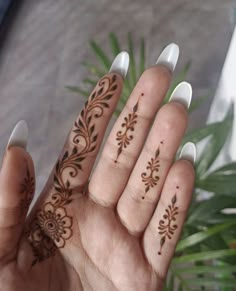 a woman's hand with hendix on it and some plants in the background