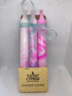 three pink and white marbled candles in a cardboard box with a ribbon on top