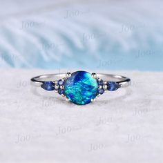 7mm Round Galaxy Blue Opal Engagement Ring Sterling Silver Cluster Blue Sapphire Ring Unique Anniversary Gift Blue Fire Opal Promise Rings 30 days non-hassle return policy. For returned items, there may be handcrafting and shipping fee deducted. DETAILS: - Material : 925 Sterling Silver (Hypoallergenic, Nickel Free, Tarnish Resistant)Solid 14k/18k gold,platinum PLEASE choose silver or platinum if you are allergic to nickel. - Main stone : 7mm Round cut blue opal - Accent Stone : blue sapphire - Blue Opal Promise Ring, Blue Birthstone Promise Ring, Blue Opal Ring Gift, Blue Opal Round Ring, Blue Round Band Jewelry Gift, Blue Round Opal Ring, Blue Opal Rings For Anniversary, Blue Opal Gemstone Ring As Gift, Blue Opal Gemstone Ring Gift