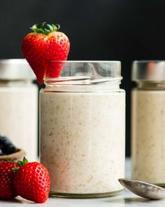 two jars filled with oatmeal and strawberries on top of a table