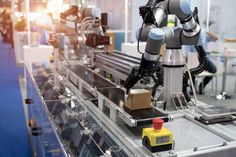 robotic arms moving along a conveyor belt in an assembly line with workers working on the machines