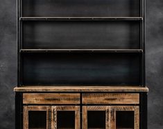 an old wooden bookcase with two doors and three drawers on one side, against a black background