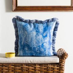 a blue and white pillow sitting on top of a wicker chair next to a mirror