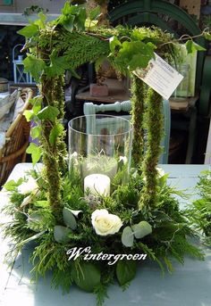 an arrangement of flowers and greenery on a table