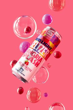 a can of fruit punch surrounded by bubbles on a pink background, with the top half falling off