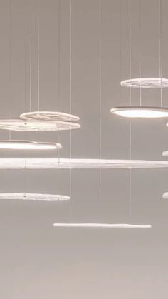 several circular lights suspended from the ceiling in a room with white walls and flooring