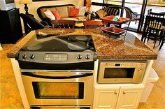 a kitchen with an oven, stove and dining room table in the backround