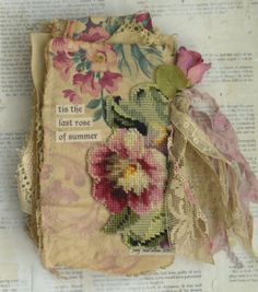 an old book with flowers and lace on it sitting on top of a piece of paper