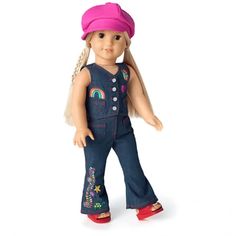 a doll with blonde hair wearing blue overalls and a pink hat, standing in front of a white background