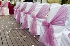 rows of white and pink chairs covered with purple sashes for an outdoor wedding ceremony