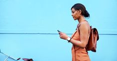 a woman walking down the street while looking at her cell phone