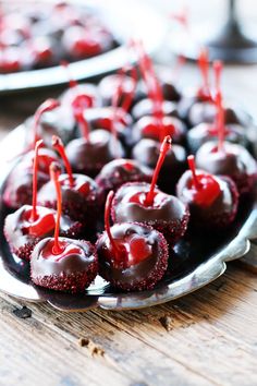 some cherries are sitting on a plate with chocolate drizzled over them