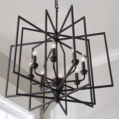 a black chandelier with candles hanging from it's center piece in a room