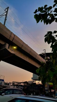 cars are parked under an overpass at sunset