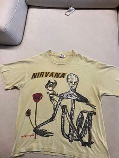 a yellow nirvana t - shirt with an image of a skeleton holding a rose on it