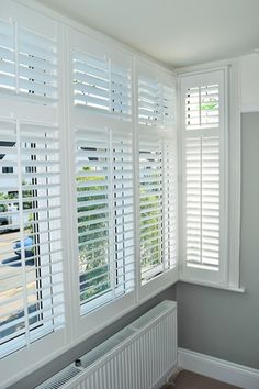 an empty room with white shutters and wood flooring