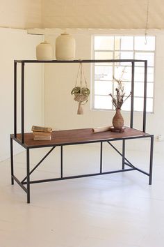 a table with two vases and books on it in front of a large window