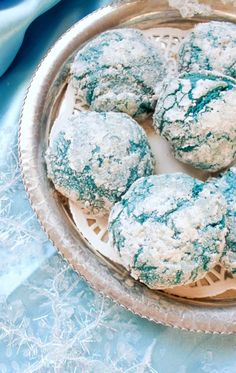 powdered sugar cookies in a glass dish on a blue tablecloth with silver trim