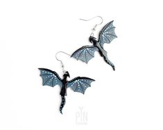 "✨ Dragon earrings measuring 4 x 5 cm (1 1/2\" x 2\") - the whole drop length is 6 cm (2 3/8\") ✨ These whimsigoth earrings are crafted from wood with sterling silver earwires ✨ The dragons are processed within 1-3 business days 🌟🐉Step into the enchanting world of fantasy with our whimsigoth dragon earrings - a captivating blend of gothic elegance and whimsical charm!  These dangle earrings are true representative of the dark academia aesthetic, and the charm of gothic style. Crafted to capture the essence of fantasy worlds, these earrings feature intricately designed dragons, hand-painted with tons of details in black and blue-gray shades and adorned with liquid glass for extra shine. Measuring the perfect length for dangle earrings, these wooden creations are suspended from sterling si Handmade Black Fantasy Earrings, Black Fantasy Earrings, Black Fantasy Style Pierced Earrings, Black Fantasy Style Earrings, Fantasy Dangle Earrings For Halloween, Fantasy Earrings For Halloween Gift, Halloween Fantasy Dangle Earrings, Fantasy Halloween Dangle Earrings, Halloween Fantasy Earrings For Pierced Ears