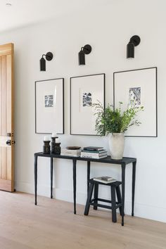 three framed pictures hang on the wall next to a table with a potted plant