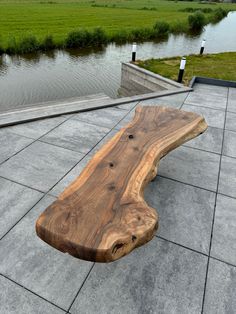 a wooden bench sitting on top of a cement floor next to a body of water