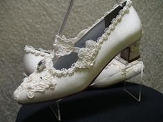 a pair of white wedding shoes with lace on the heel and heels are sitting on top of a black chair