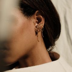 a close up of a person wearing large gold earrings and a white shirt