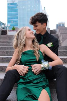 a man and woman are sitting on the steps in front of some stairs with their arms around each other